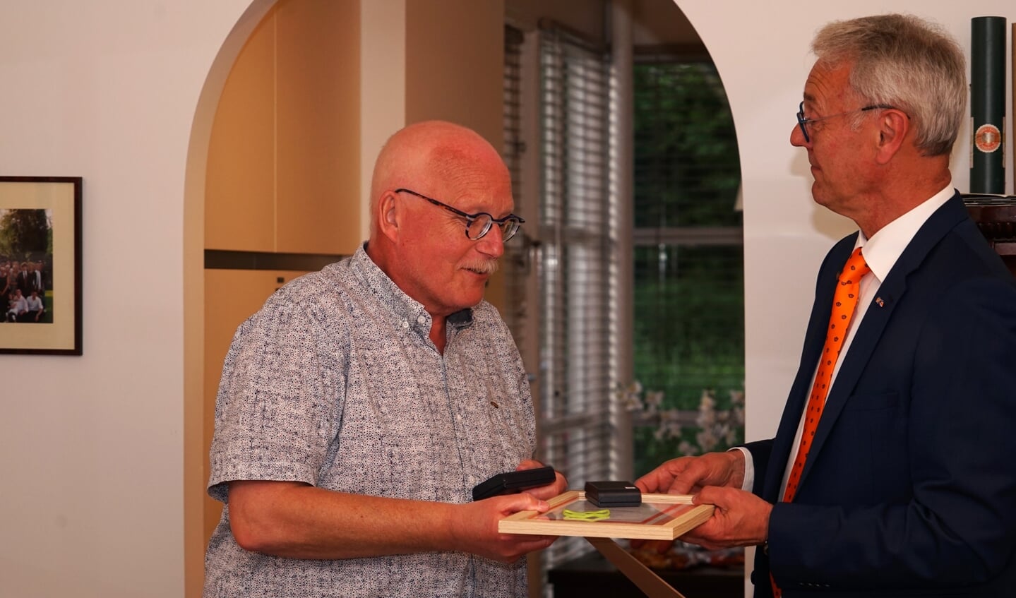 Bestuurslid Hans Janssen van de landelijke Bond van Oranjeverenigingen overhandigt erepenning en bijbehorend certificaat aan Arno Mentink.