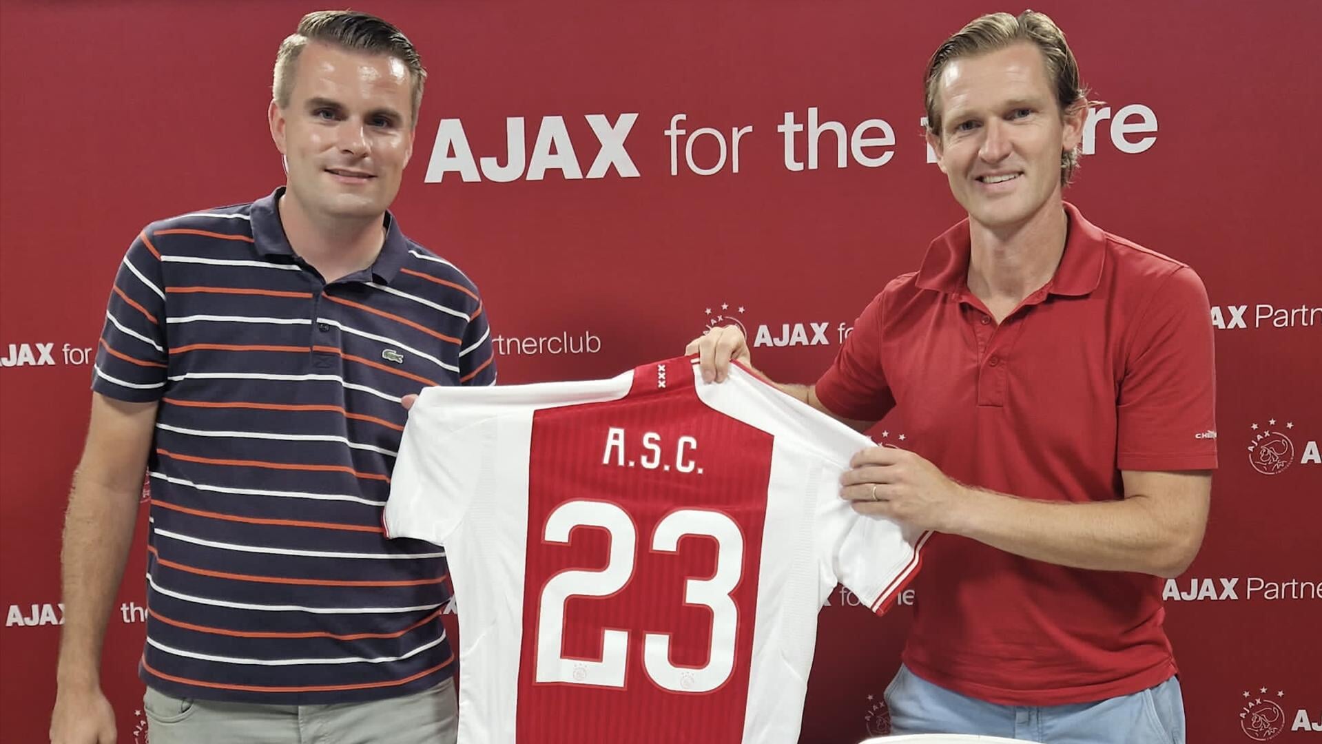 Hoofd Jeugdopleiding Cor Stols (Ajax) en jeugdvoorzitter Julius Janssen van ASC tonen trots het shirt dat Ajax bij het tekenen aan het Oegstgeester Ajax heeft geschonken.