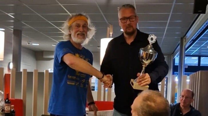 Clubsecretaris Arnold van Steijn reikt de beker uit aan kampioen Jaap Meiland.