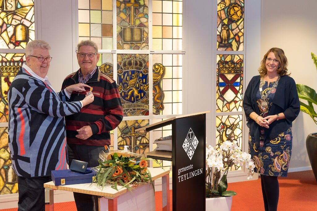 Wim Berg krijgt de koninklijke onderscheiding opgespeld door zijn vrouw Nel. | Foto: pr./Sven van der Vlugt