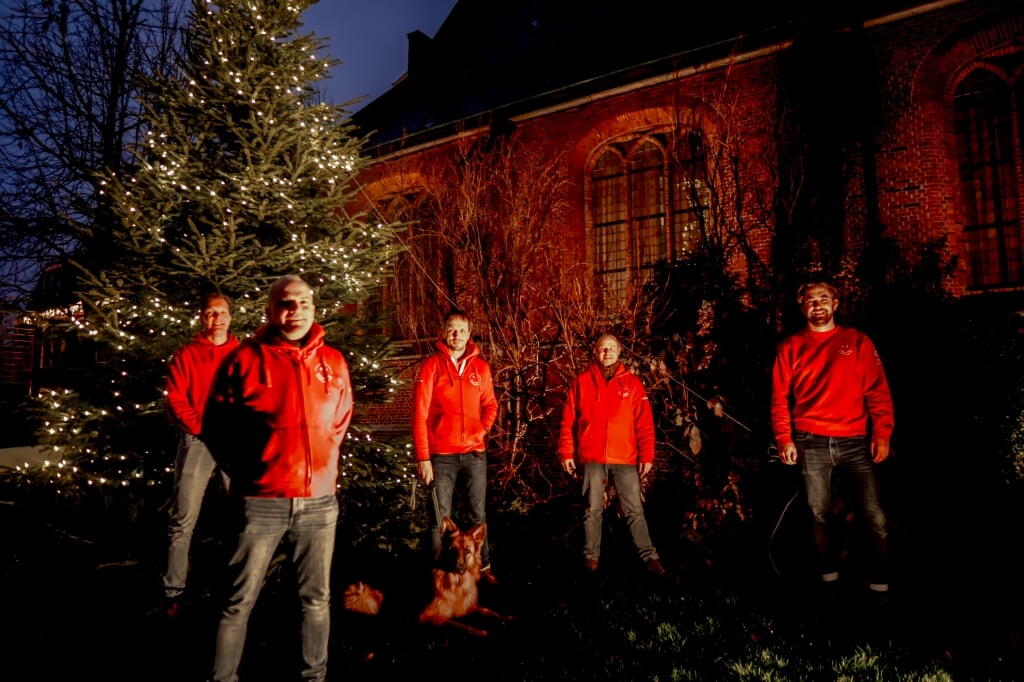 Voorzitter Herbert Zilverentant (linksvooraan) en vier bestuursleden van de Vrienden van het Oude Dorp bij de verlichte kerstboom. | Foto: J.P. Kranenburg