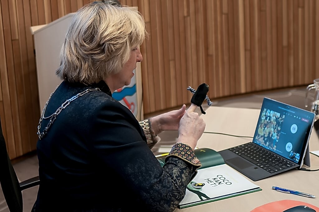 Burgemeester Driessen, met Coco-vingerpoppetje, achter haar laptop waarop ze haar jonge publiek ziet. | Foto: J.P. Kranenburg 
