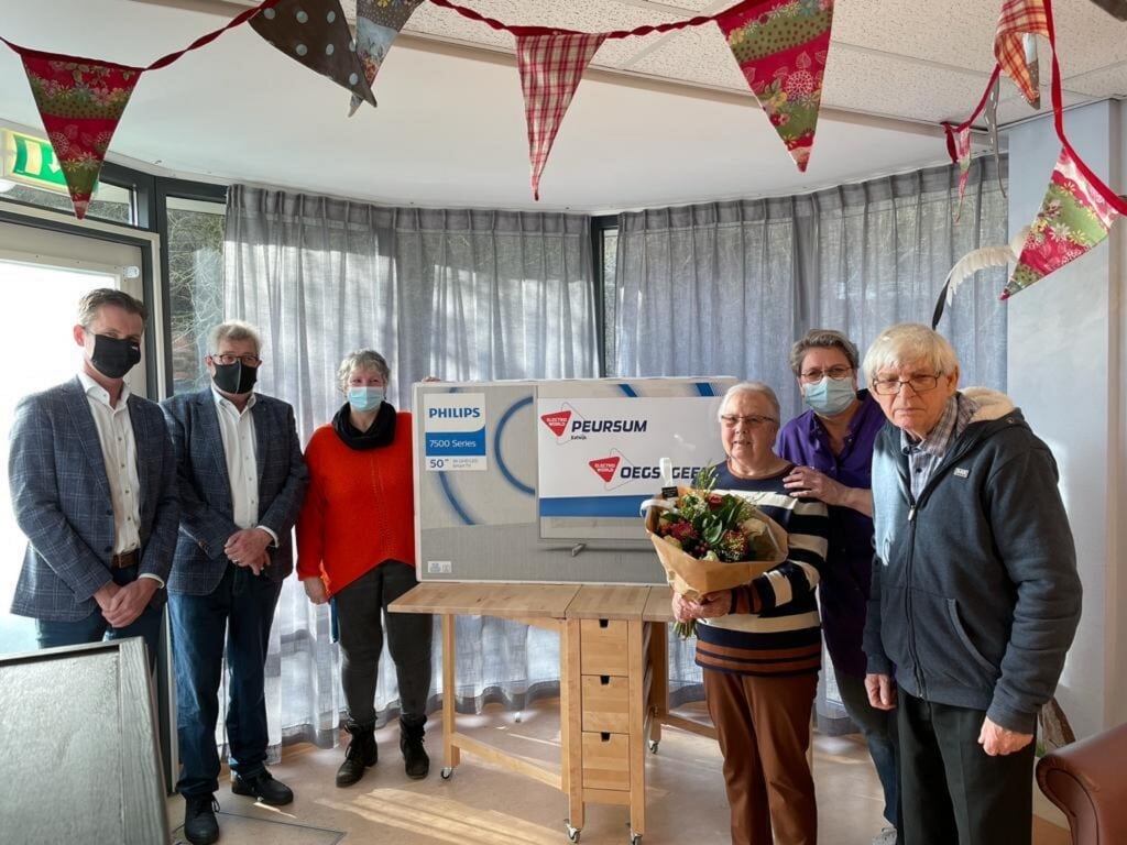 Kees-Jan te Nijenhuis en Jan van Woerkom (link) van Electro World reiken de televisie uit aan Gonnie van Rijn en bewoners van de afdeling Esdoorn op Overduin. | Foto: pr