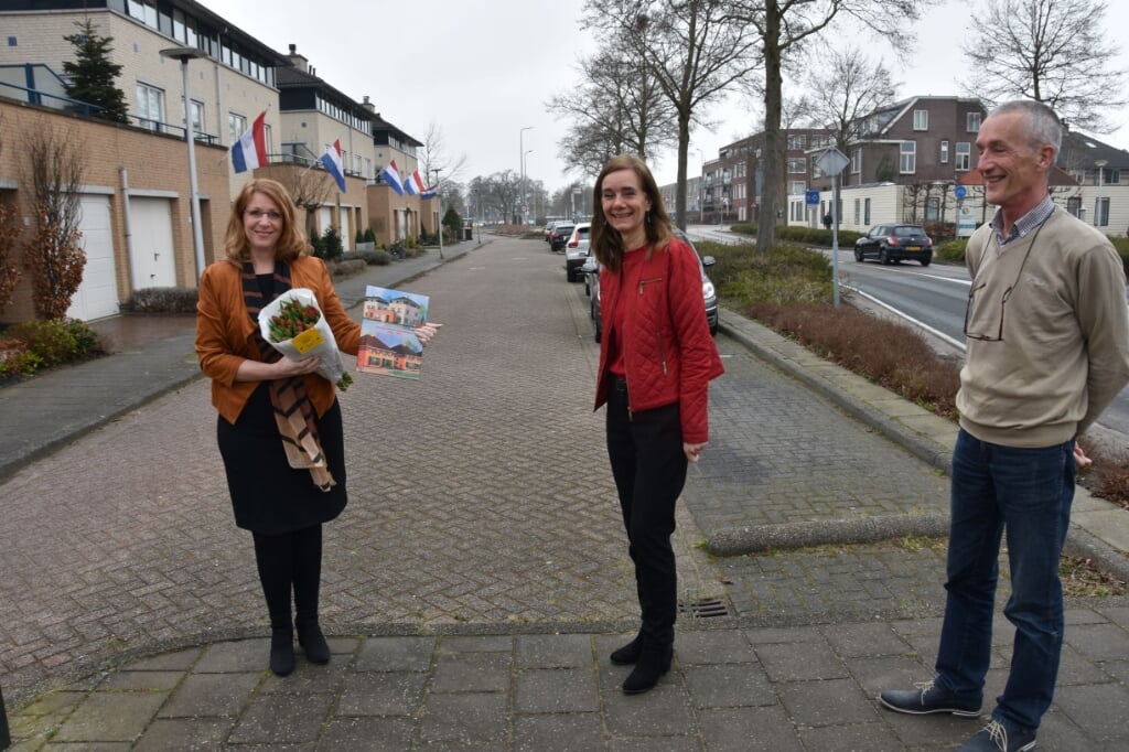 Mariette van Niftrik (m) en schrijver Eugene van de Poel (r) overhandigen het jubileumboek aan de burgemeester. 
