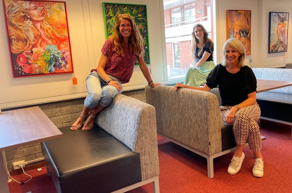Marleen Dijkdrent (links) samen met bibliotheekmedewerkers Anne Pauwels en Irene van der Plas, voor een aantal schilderijen van haar kunstproject Ontmoet Jouw Wilde Zelf! in de hoofdbibliotheek. | Foto: pr