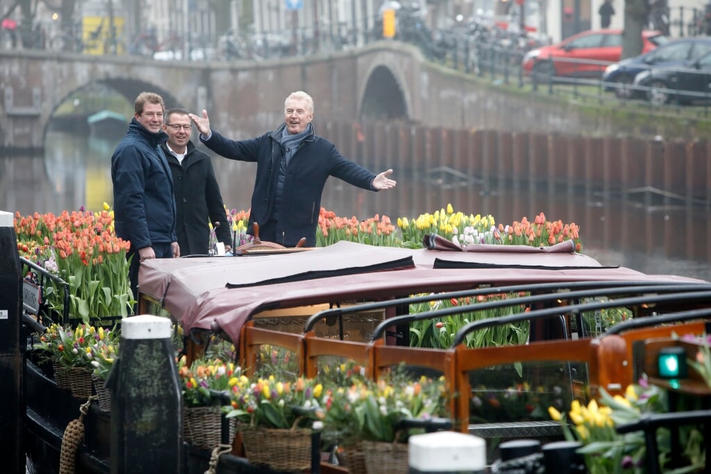 André van Duin nodigt met zijn gulle gebaar het publiek uit van de tulpen te genieten.