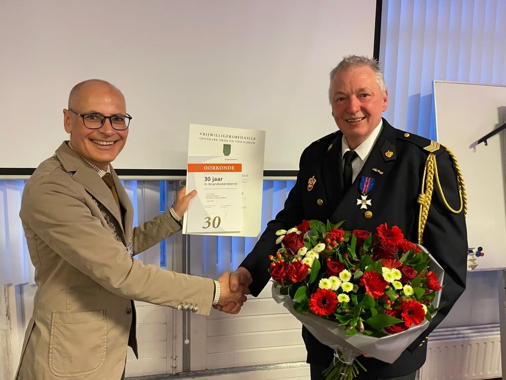 Burgemeester Jaensch feliciteert Hans Rutten met dertig jaar brandweer.