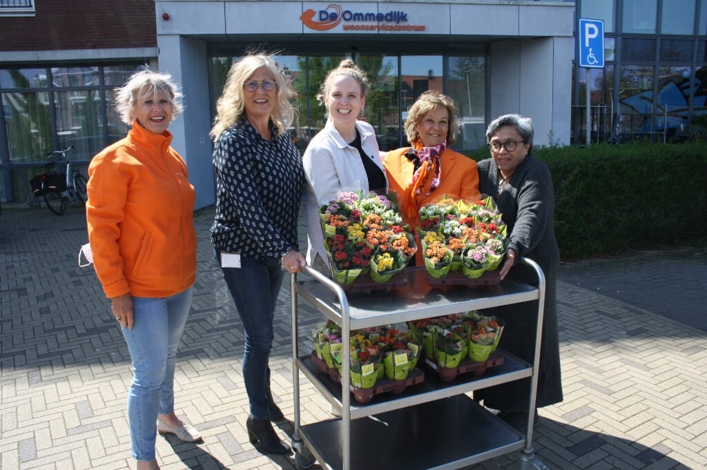 Rina Cooijmans en Tineke Zonneveld van de Oranjevereniging Leiderdorp overhandigen de bloemenhulde aan Willeke van Delft, Tessa de Rooij en en Yvette Wattimury van De Ommedijk. | Foto: PR OVL