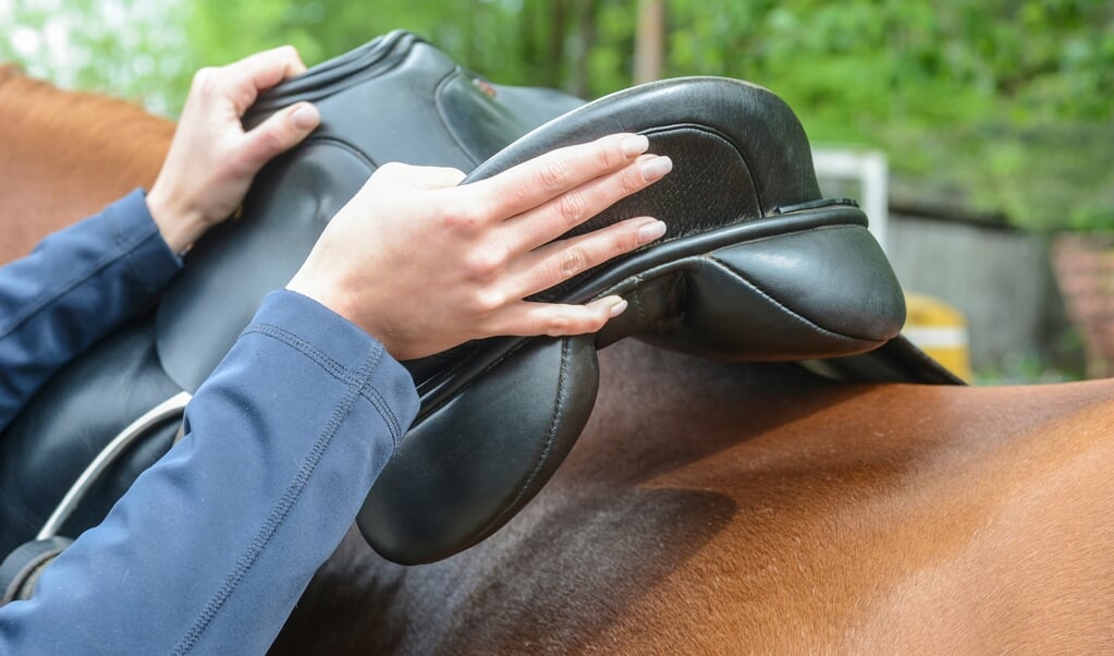 human hand is setting the saddle