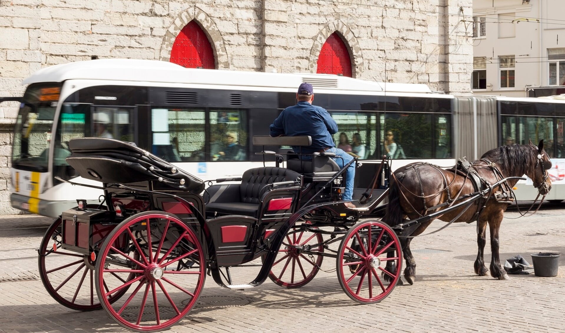 Old style carriage with bored coachman against modern bus