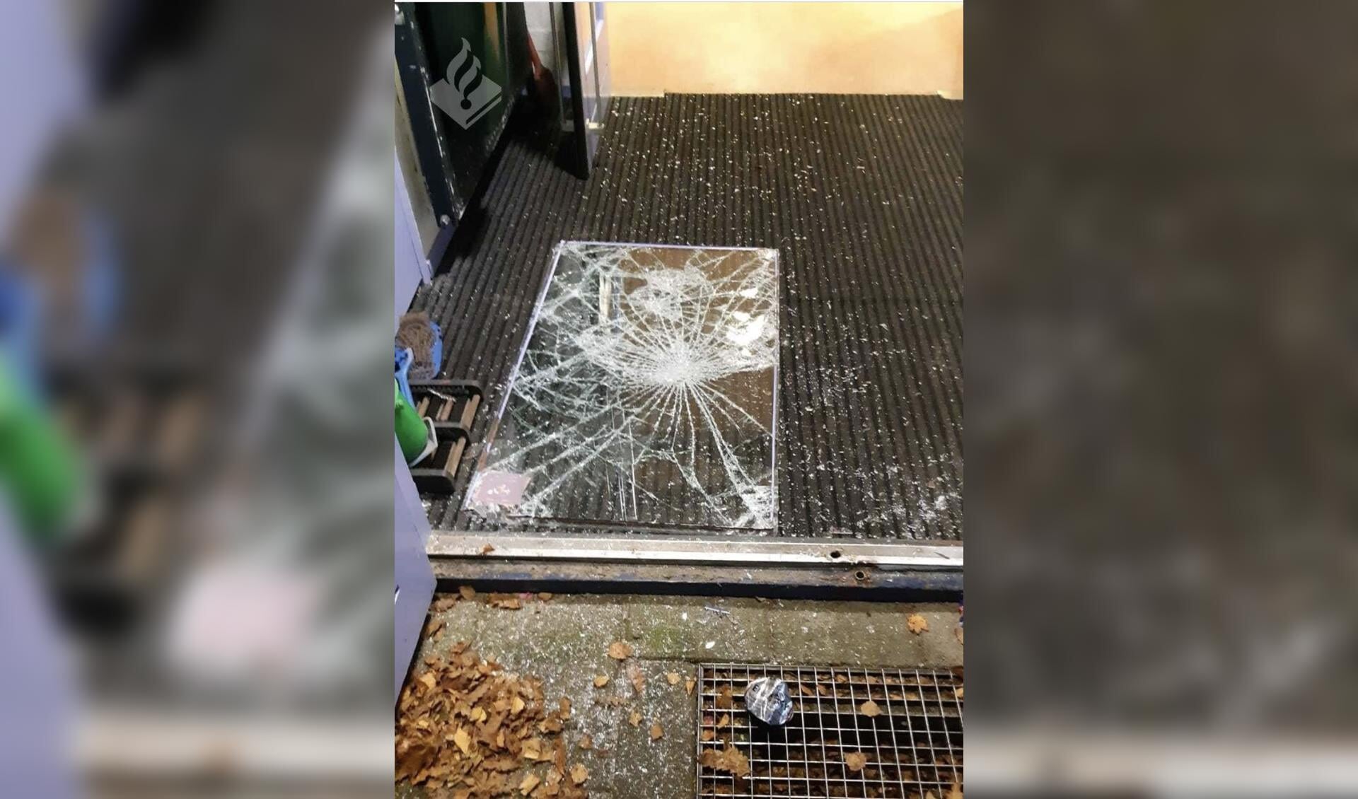 Het kapotte raam dat uit de voordeur van de basisschool was geslagen door de inbreker.
