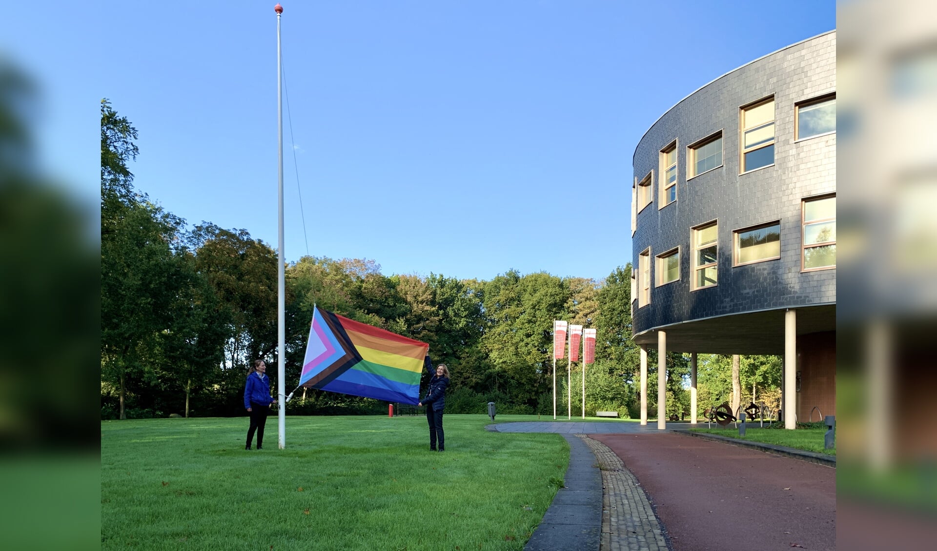 Wethouder Esther Verhagen hijst de Progress Flag voor het gemeentehuis in Oosterwolde. 