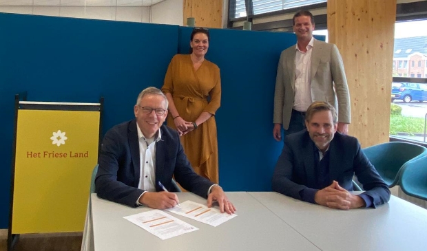 Klaas Kuilman, directeur van Thuiszorg Het Friese Land (zittend links), en Erik Wijnhof, directeur van Zorgcentrale Noord (zittend rechts) ondertekenen het nieuw contract, Ypie Duursma-Groenewoud van Thuiszorg Het Friese Land en Maarten den Heijer van Zorgcentrale Noord kijken toe.