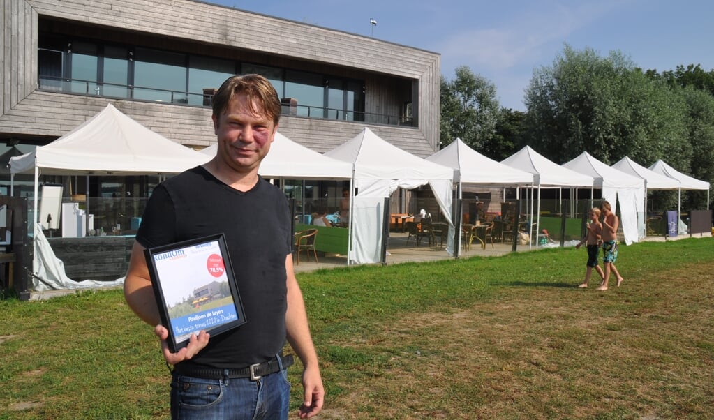 Mede-eigenaar Pier staat voor zijn terras met de award