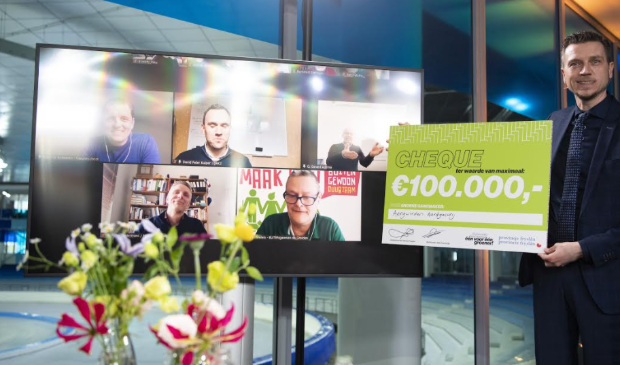 Wethouder Jelle Zoetendal reikt met de ijsbaan van Thialf op de achtergrond virtueel de 100.000 euro per project uit aan de vijf gelukkige winnaars.