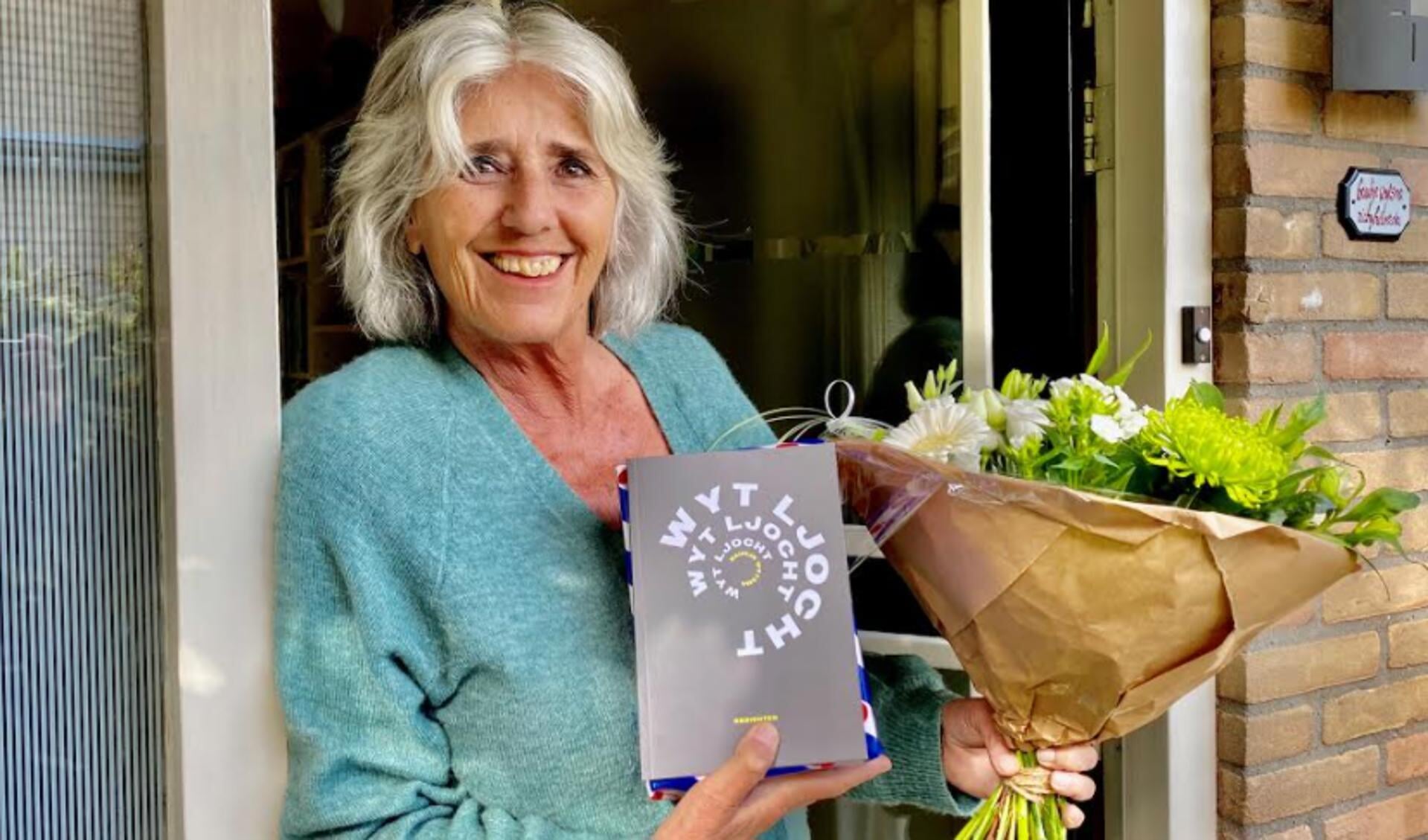 Baukje Wytsma ontvangst een bos bloemen en het eerste exemplaar van haar nieuwste dichtbundel, uit handen van de directeur van de AFÛK.