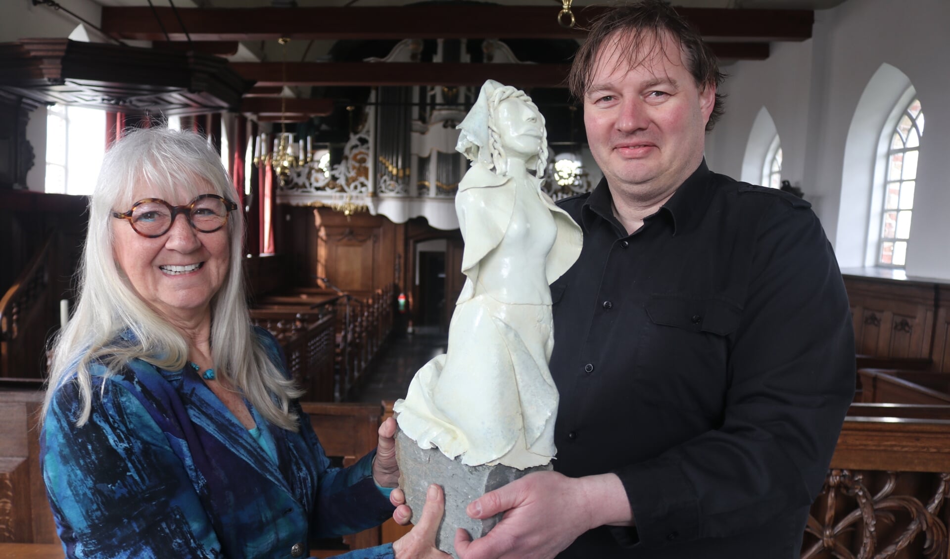 Kunstenares Rian Vis van Heemst overhandigt het beeld van Anna Maria van Schurman aan gids Stephan Kurpershoek.