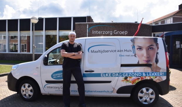 Teamleider Rob Scholten van de Maaltijdservice poseert met één van de bezorgbussen.