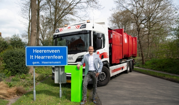 <p>Wethouder Jaap van Veen poseert samen met een Omrin-vuilniswagen bij een bord van Heerenveen.</p>