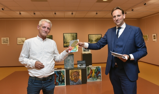 <p>Wethouder Hoen reikt het eerste exemplaar uit van het boek over de cultuursector in coronatijd.</p>