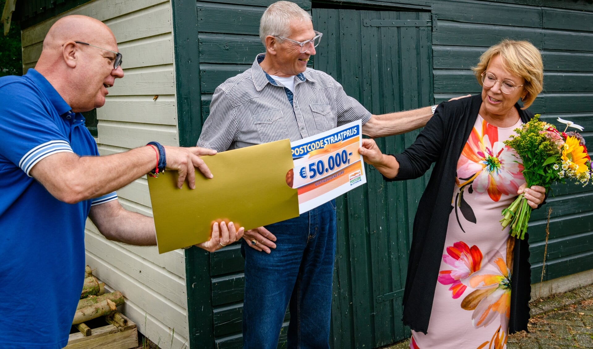Marijke en Allan ontvangen cheque van 50.000 euro van Postcode Loterij-ambassadeur Gaston Starreveld. 