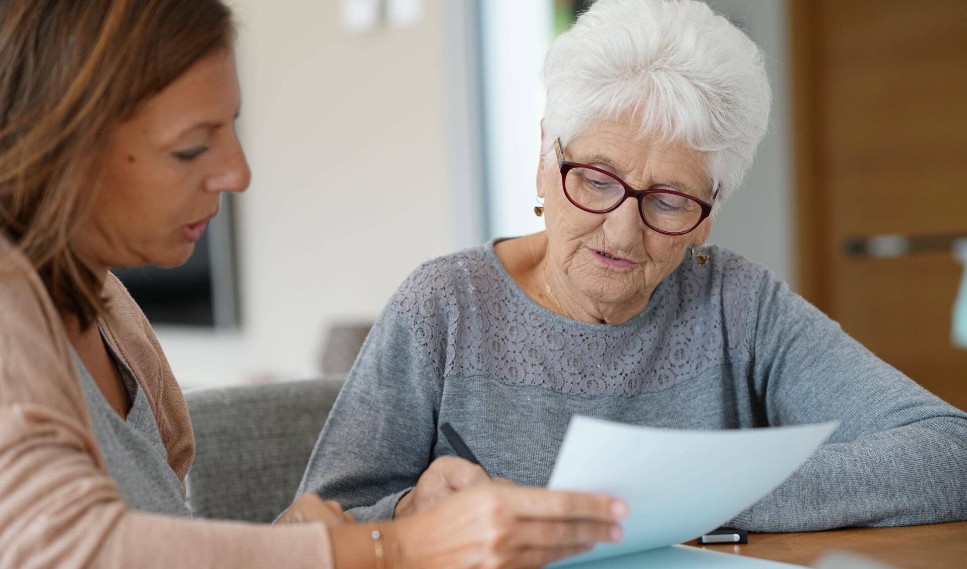 Home assistant helping elderly woman with paper work