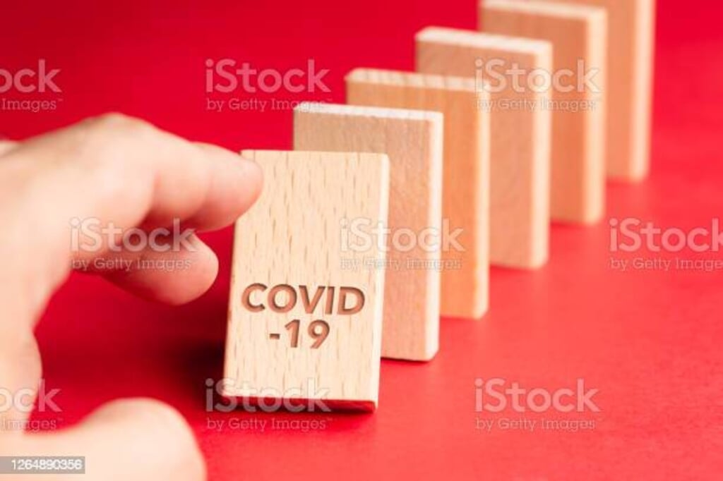 Closeup hand push the first domino of Covid-19 and going to fall down to the others, consequences of Covid-19 pandemic