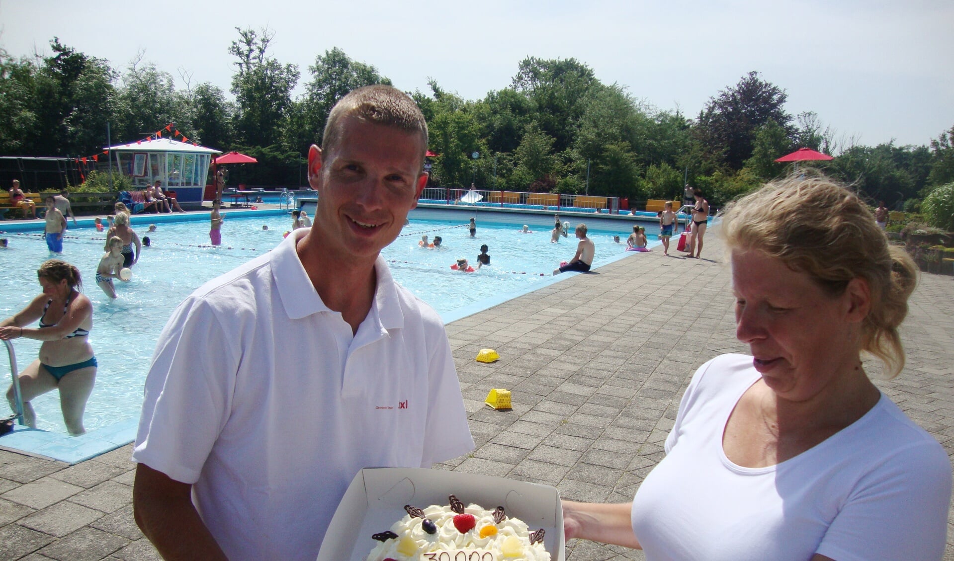 Badmeester Remko Spelde overhandigt een taart aan 30.000ste bezoeker Ingrid Neuman uit Westzaan. (Foto March Heijnen)