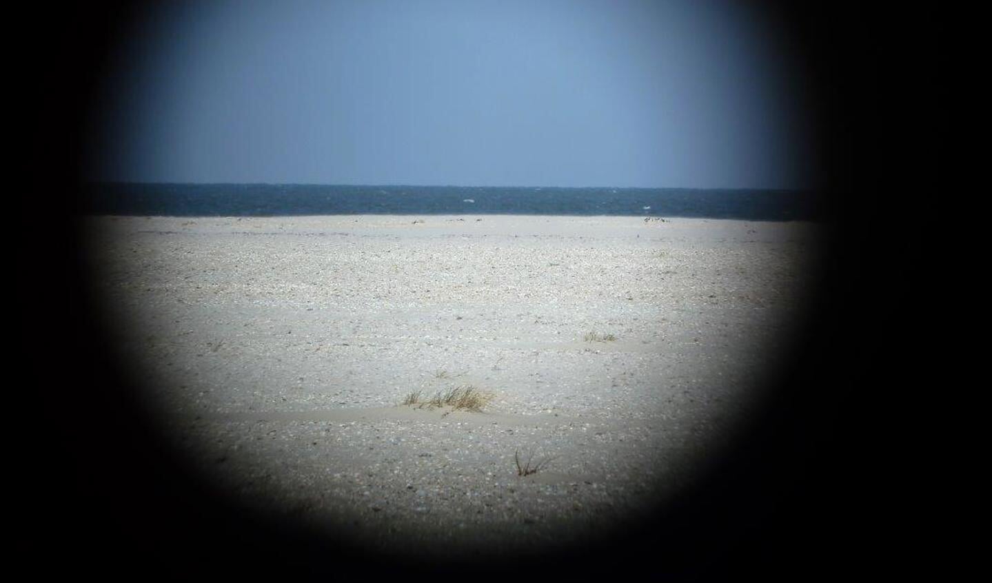 De foto is gemaakt Ron Maasland en hij is genomen bij de vuurtoren en dan door het gat van een strandpaal heen.