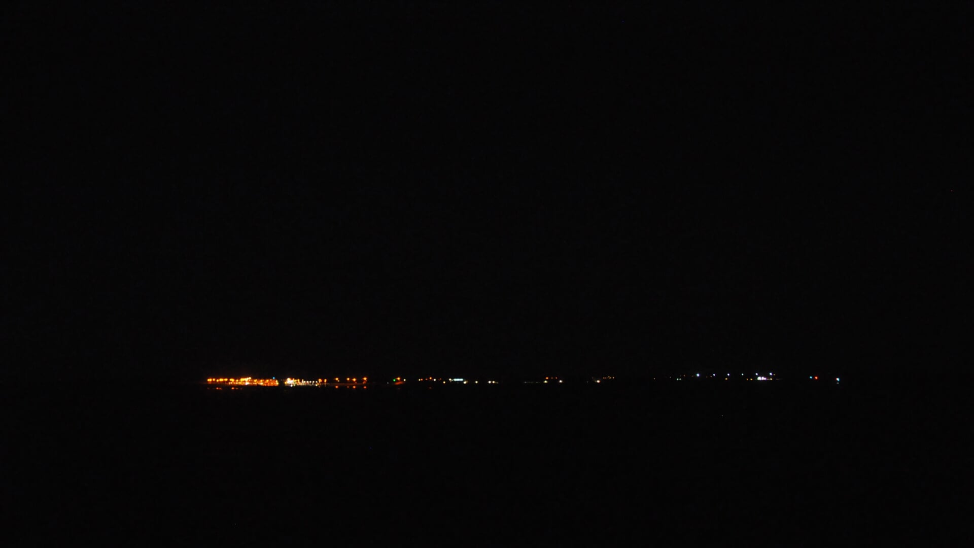 Uitzicht op een vrijwel donker Texel vanaf de boot. De lichten links zijn van de veerhaven.