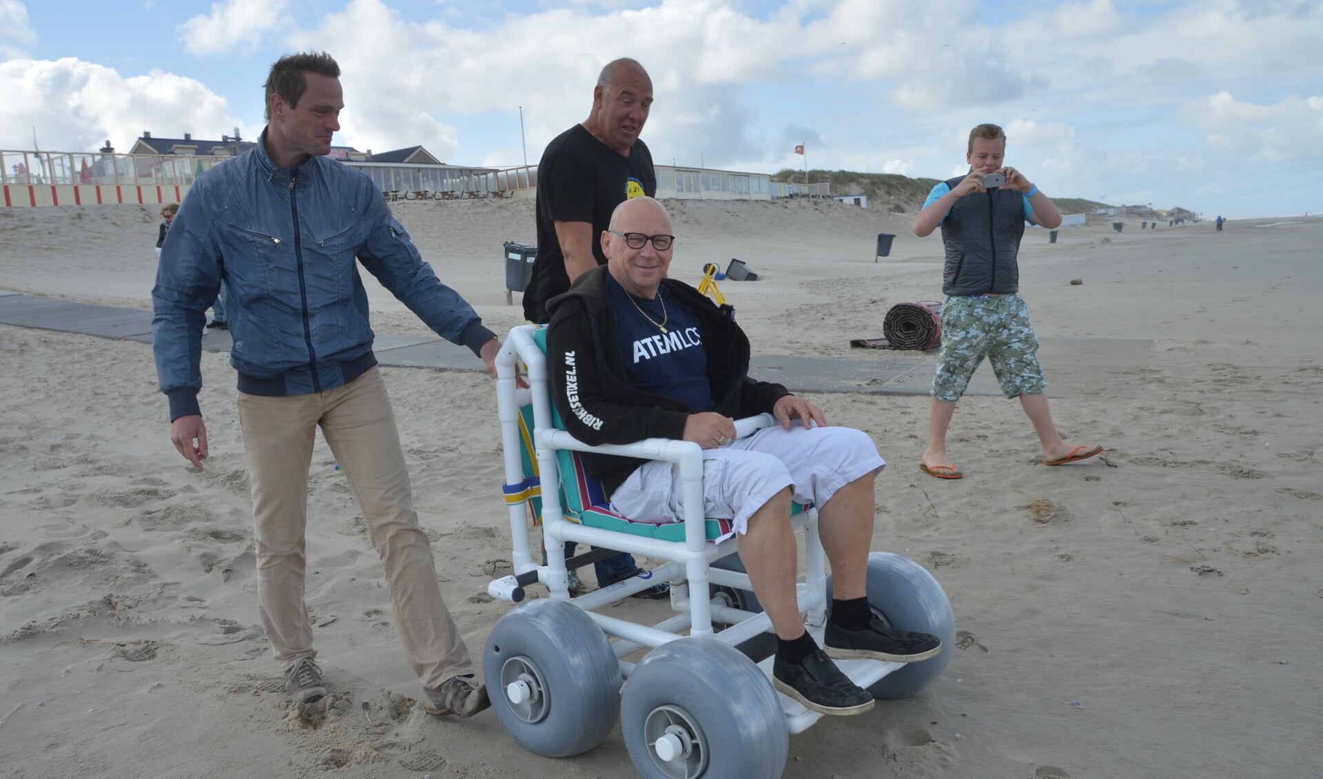Paul van Dijk probeert de nieuwe rolstoel even uit, voortgeduwd door Jan van der Star en Stephan Kikkert.