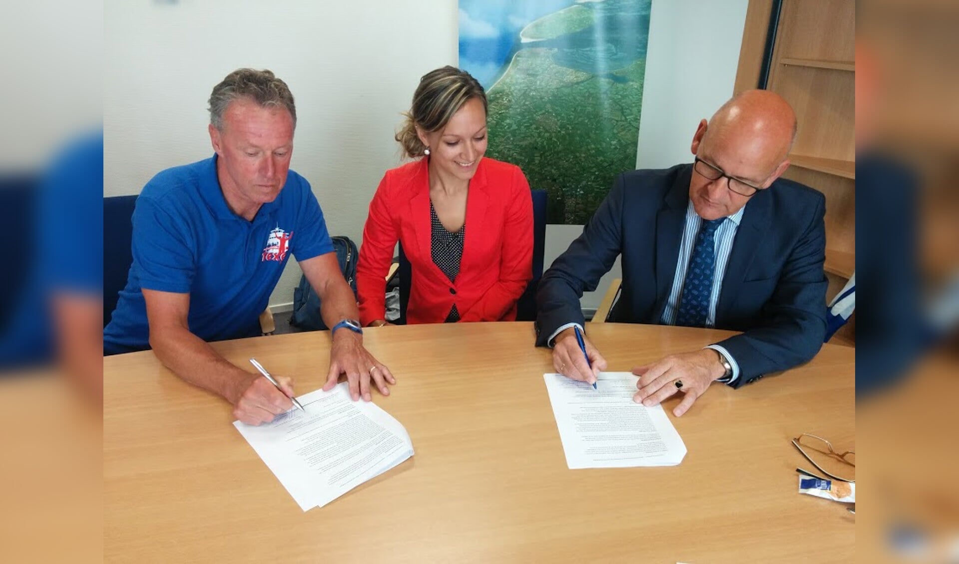 Dick van der Weide en Harry Nieuwenhuizen tekenen de contracten. Medewerkster Iris Barhorst van de bank is daarbij aanwezig, omdat zij dit jaar de 10 kilometer loopt.