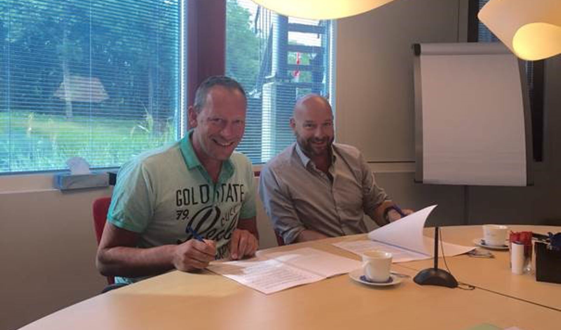 Elmar Keijser en Frits Nieuwenhuizen (directeur/eigenaar NHbioscopen) tekenen de overeenkomsten.