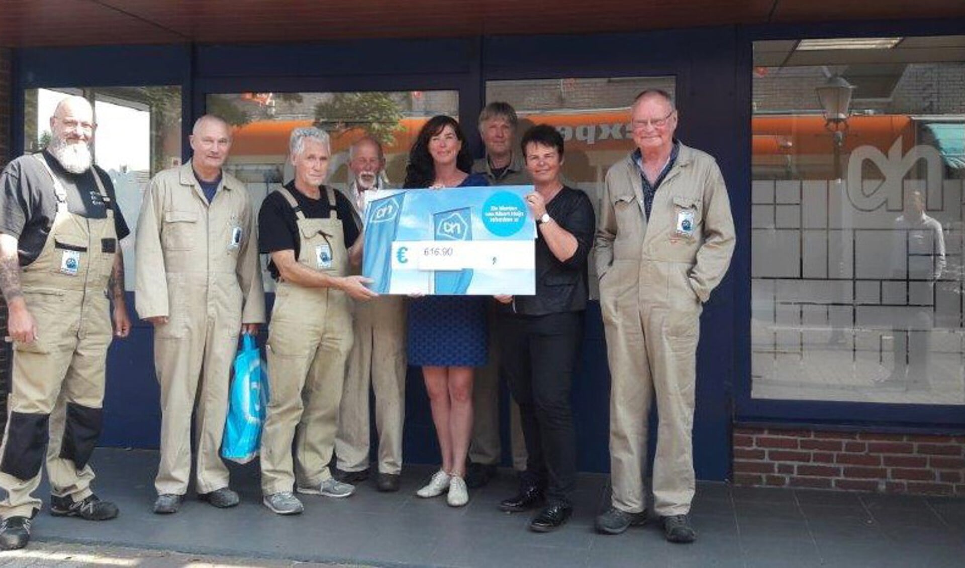 Molenaars (vlnr) Willem Stolk, Ron Latjes, Klaas Veenbaas, Dirk Haker, Leendert Pieterse, Arie de Ligt, en museummanager Corina Hordijk nemen de cheque in ontvangst van supermarktmanager Sietske de Boer