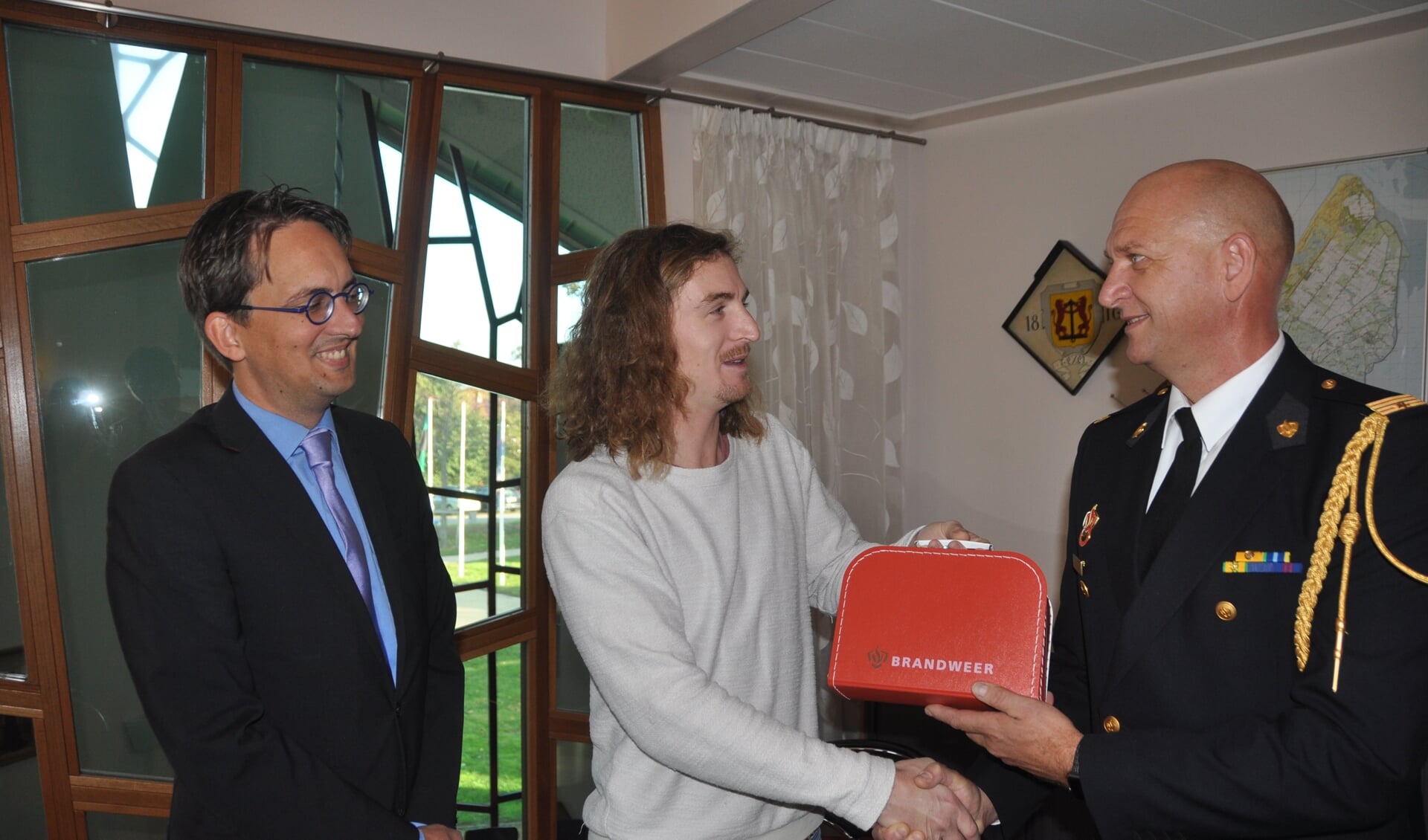 Wouter Krab krijgt de geboortekoffer van de brandweer uit handen van brandweercommandant Jelle de Boer en burgemeester Michiel Uitdehaag.