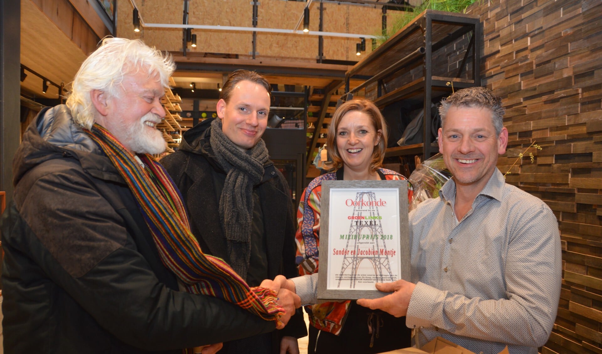 Jaap Vlaming en Sander van Knippenberg overhandigen de Groen Links Milieuprijs aan Sandor en Jacobine Mantje bij de opening van hun nieuwe winkel in De Koog. 