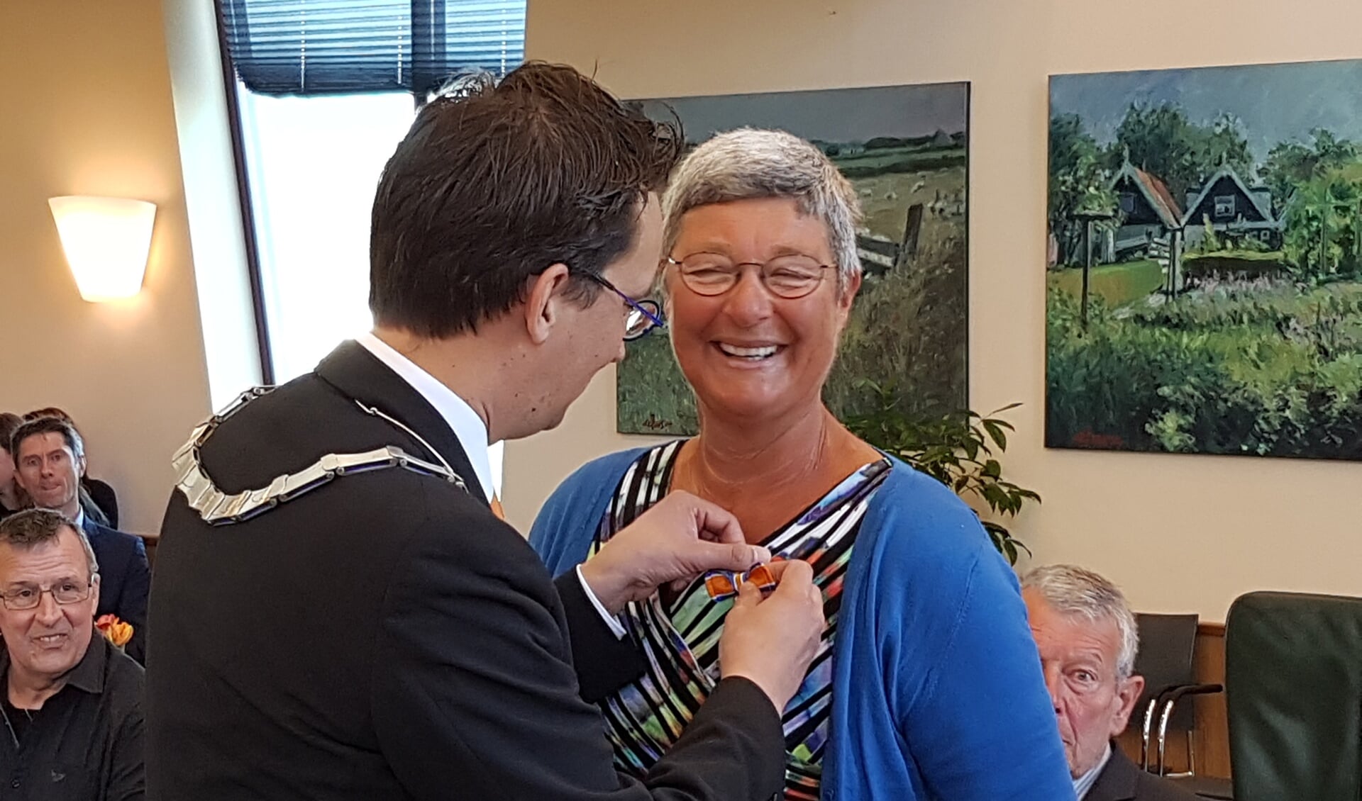 Burgemeester Uitdehaag speldt Rita Dogger haar lintje op. 