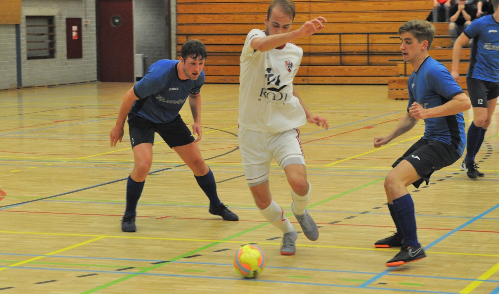 Jesper Arkenbout en Jesper List van Texel'94 Futsal en een speler van White Stones in duel om de bal. 