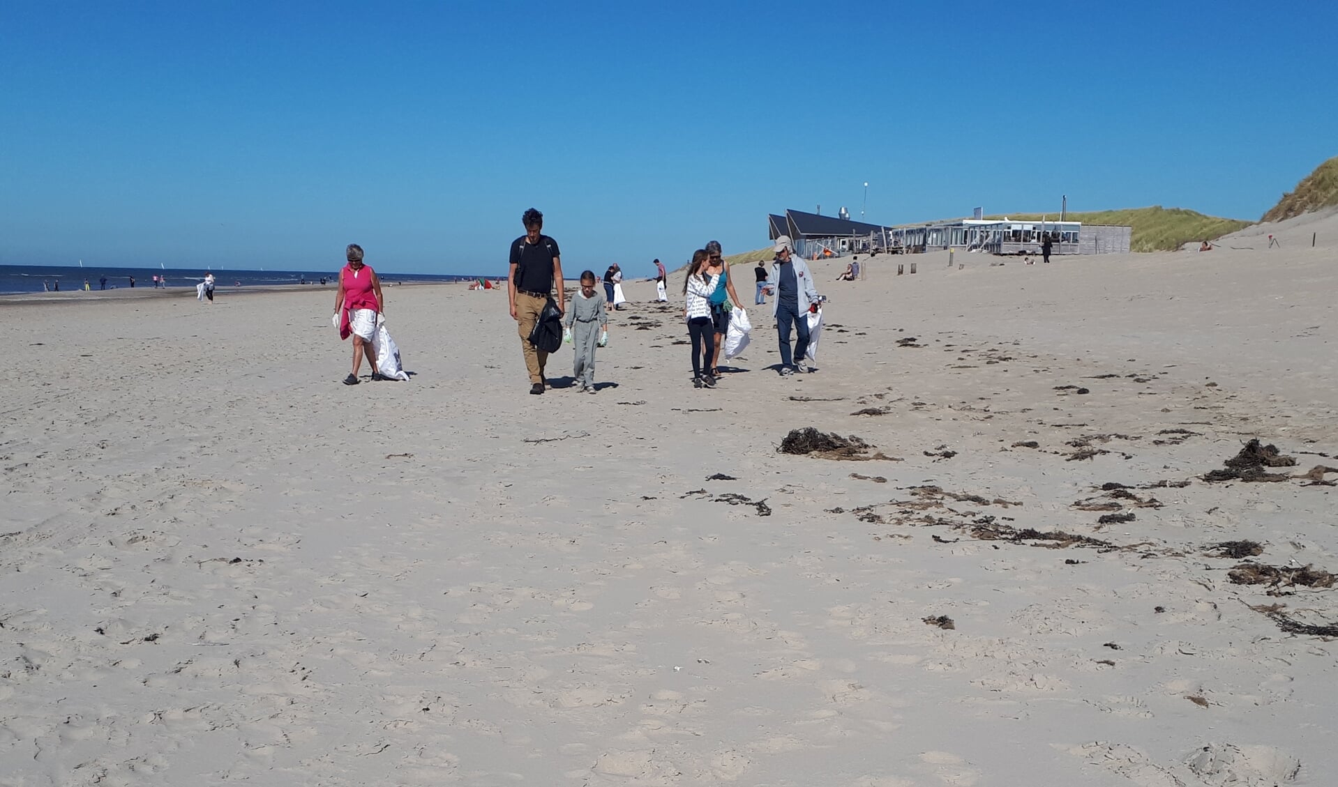 Het ruimen van stukjes plastics op het strand bij paal 15.