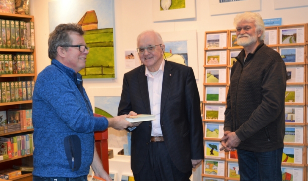 Schrijver Koos Terpstra overhandigt het eerste exemplaar van "Mijn Eiland" aan zijn oud-leraar Hennephof (midden). Het tweede exemplaar was voor wethouder Jaap Vlaming.