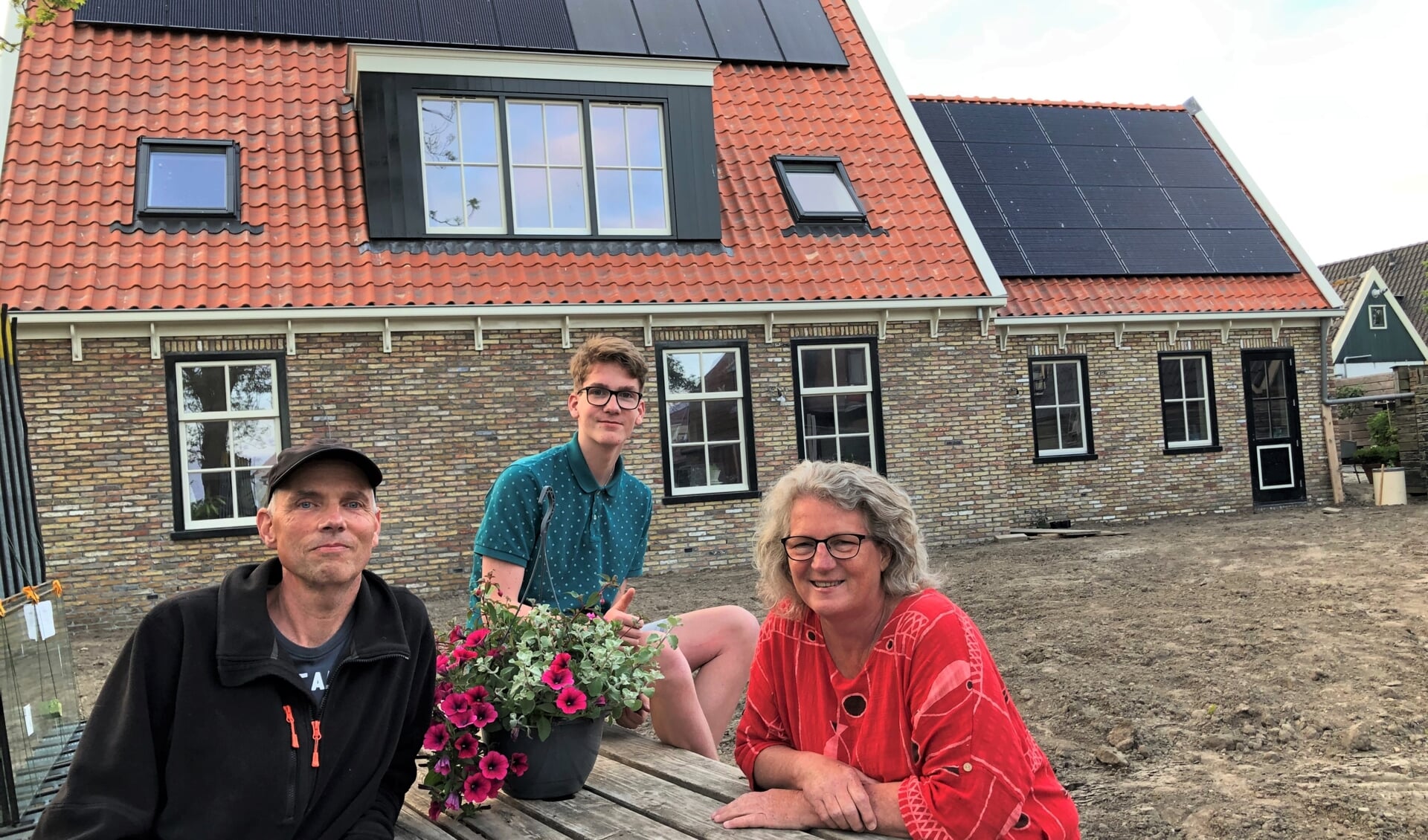 Bart, Stefan en Leni Eveleens voor hun nieuwe woning, herbouwd na de verwoestende brand begin maart 2018. 
