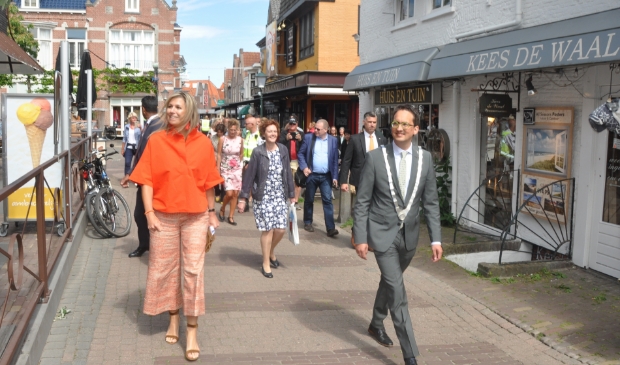 Koningin Maxima loopt begeleid door burgemeester Michiel Uitdehaag door Den Burg.