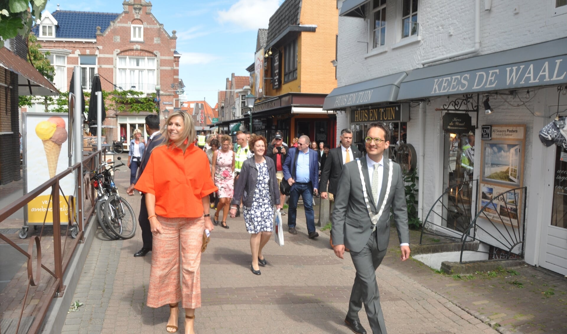 Koningin Maxima loopt begeleid door burgemeester Michiel Uitdehaag door Den Burg.