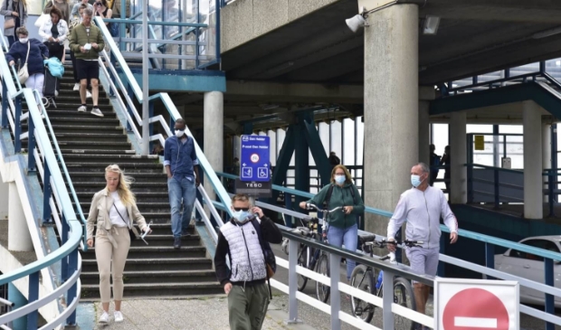 Reizigers die van de boot komen, zijn voorzien van mondkapjes.