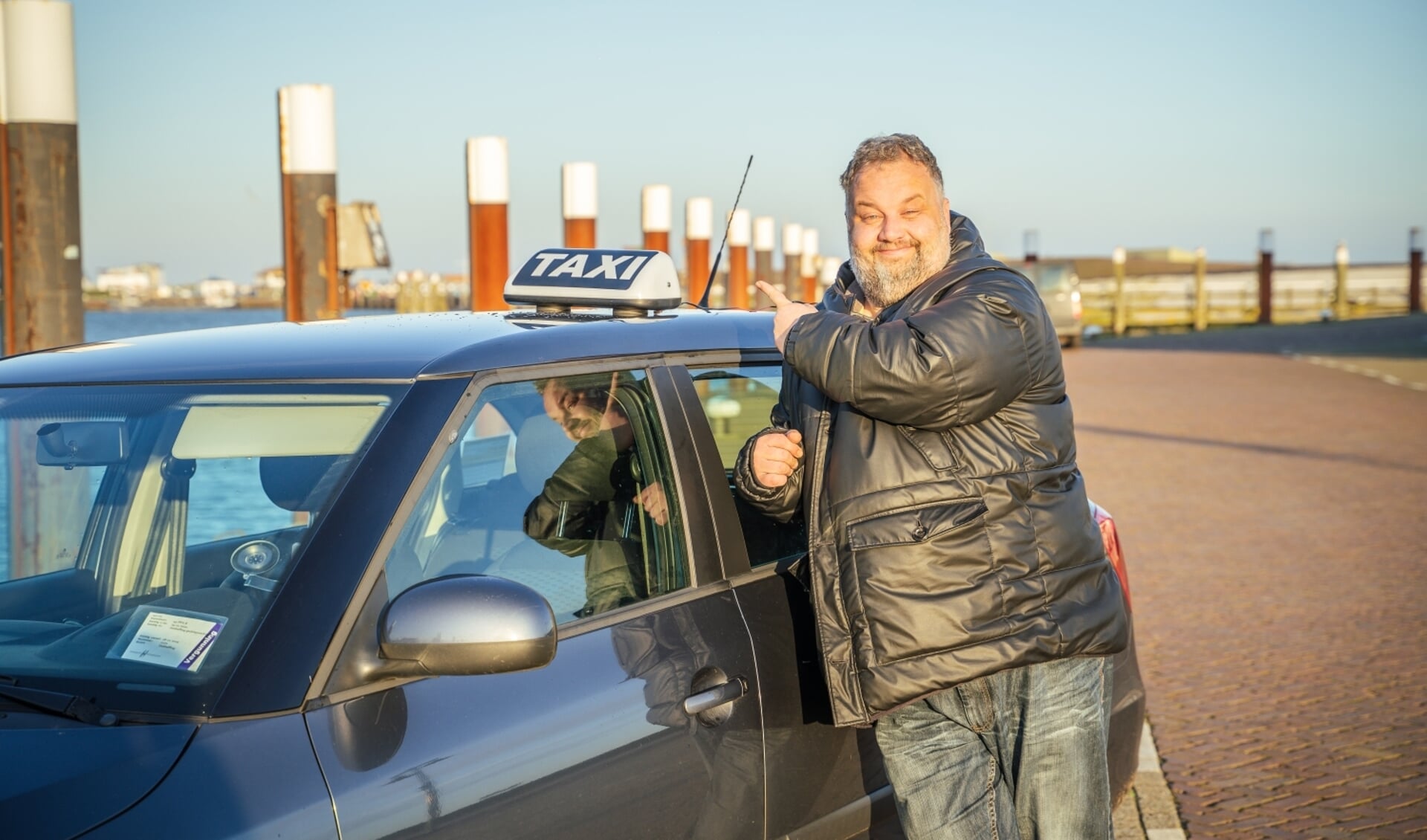 Raymond Korf bij zijn taxi op de haven van Oudeschild.