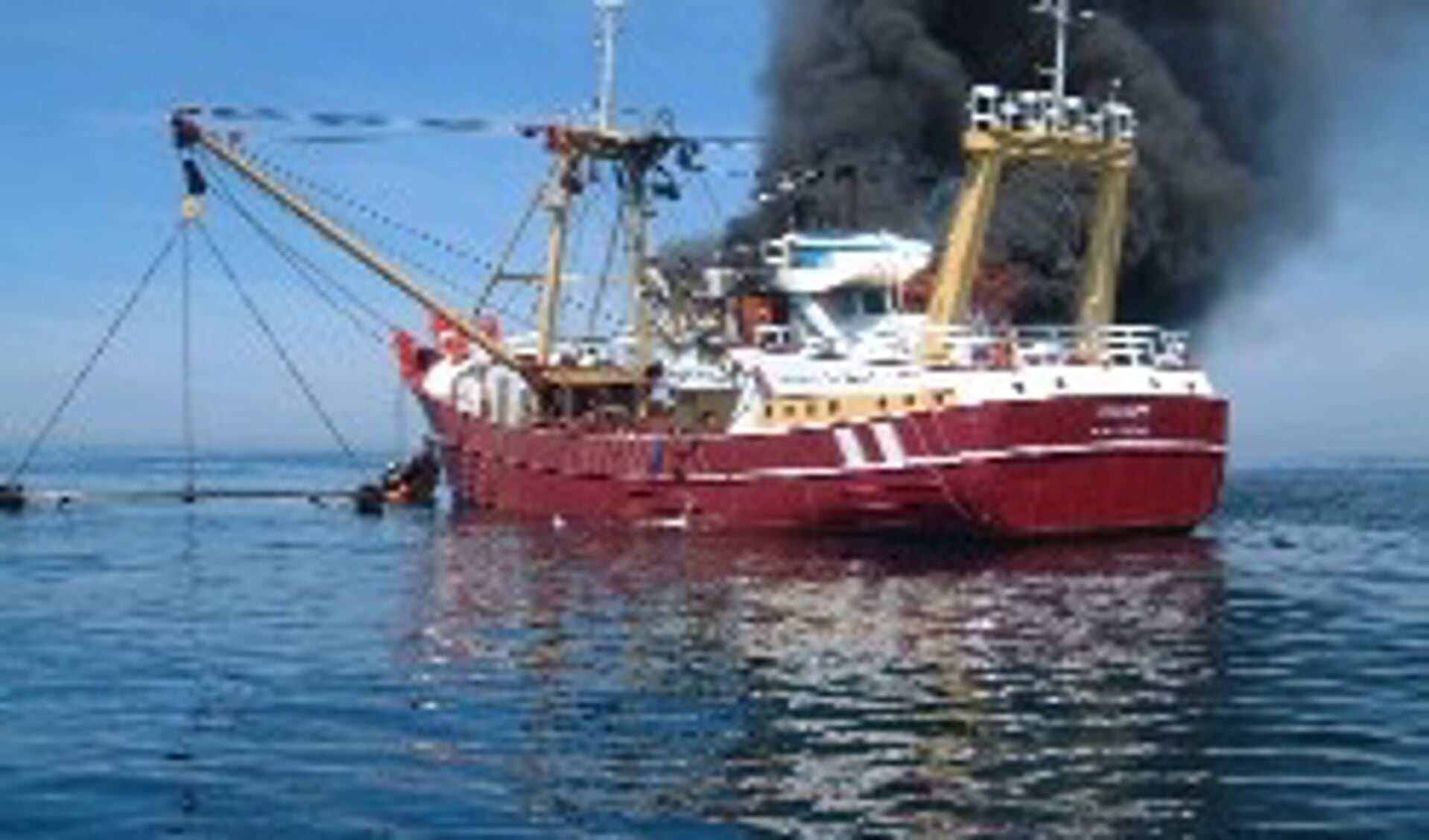 De kotter Johannes uit Stellendam staat in brand. De bemanning staat voorop het schip om hulp te roepen. (foto Rutgert O