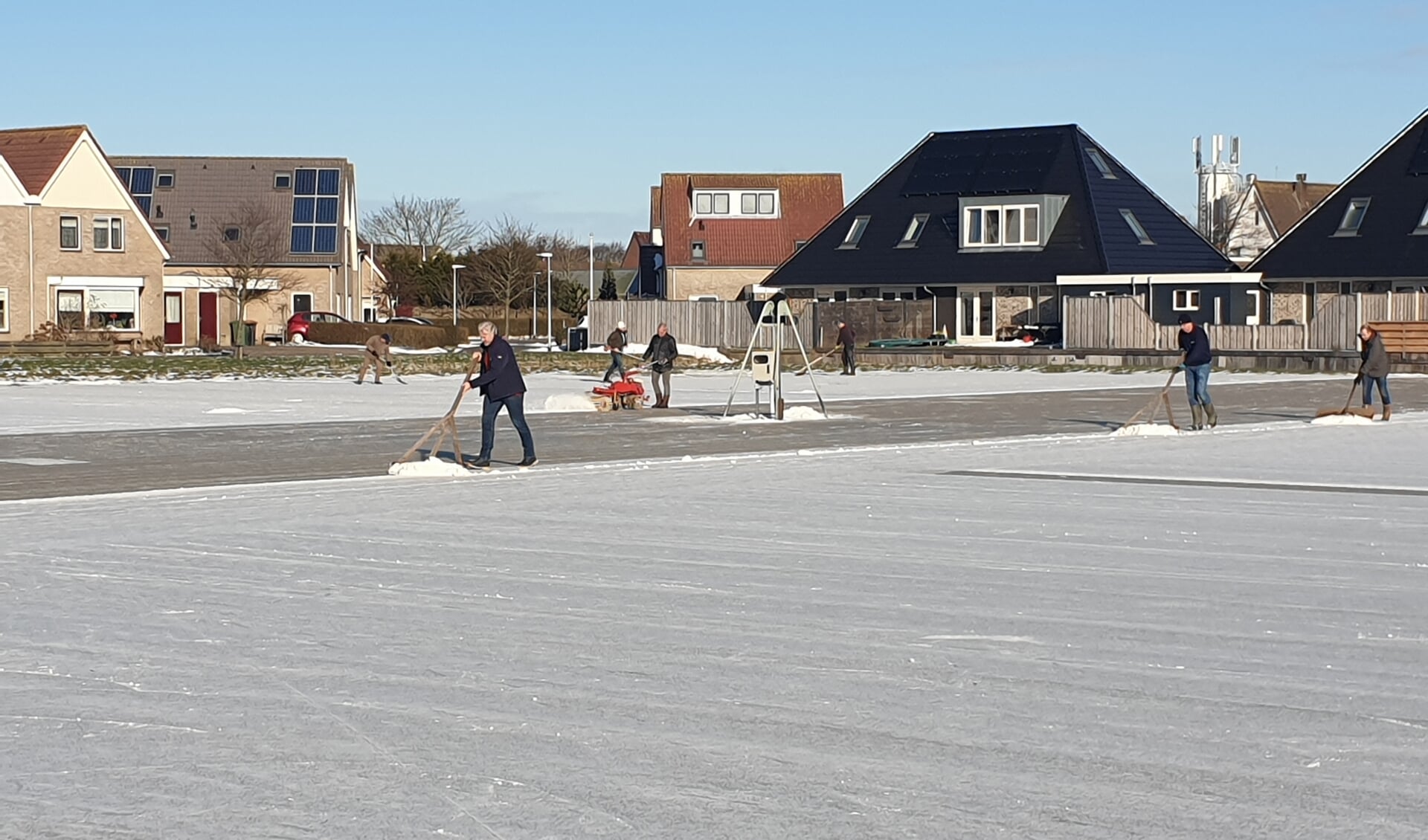 Vrijwilligers in Oudeschild maken de ijsbaan sneeuwvrij.