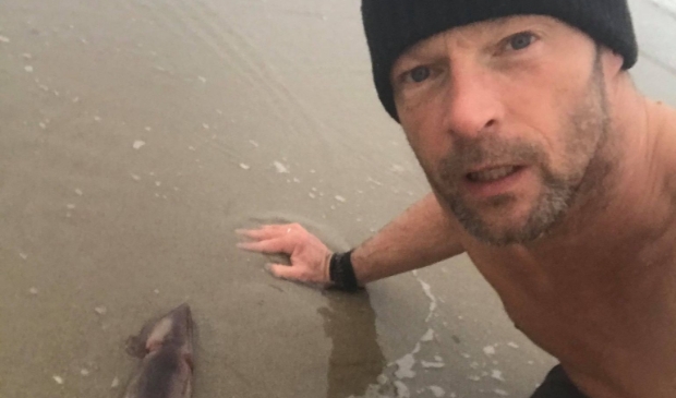 <p>Ruud van Holland met de pijlinktvis op het strand bij paal 28.</p>