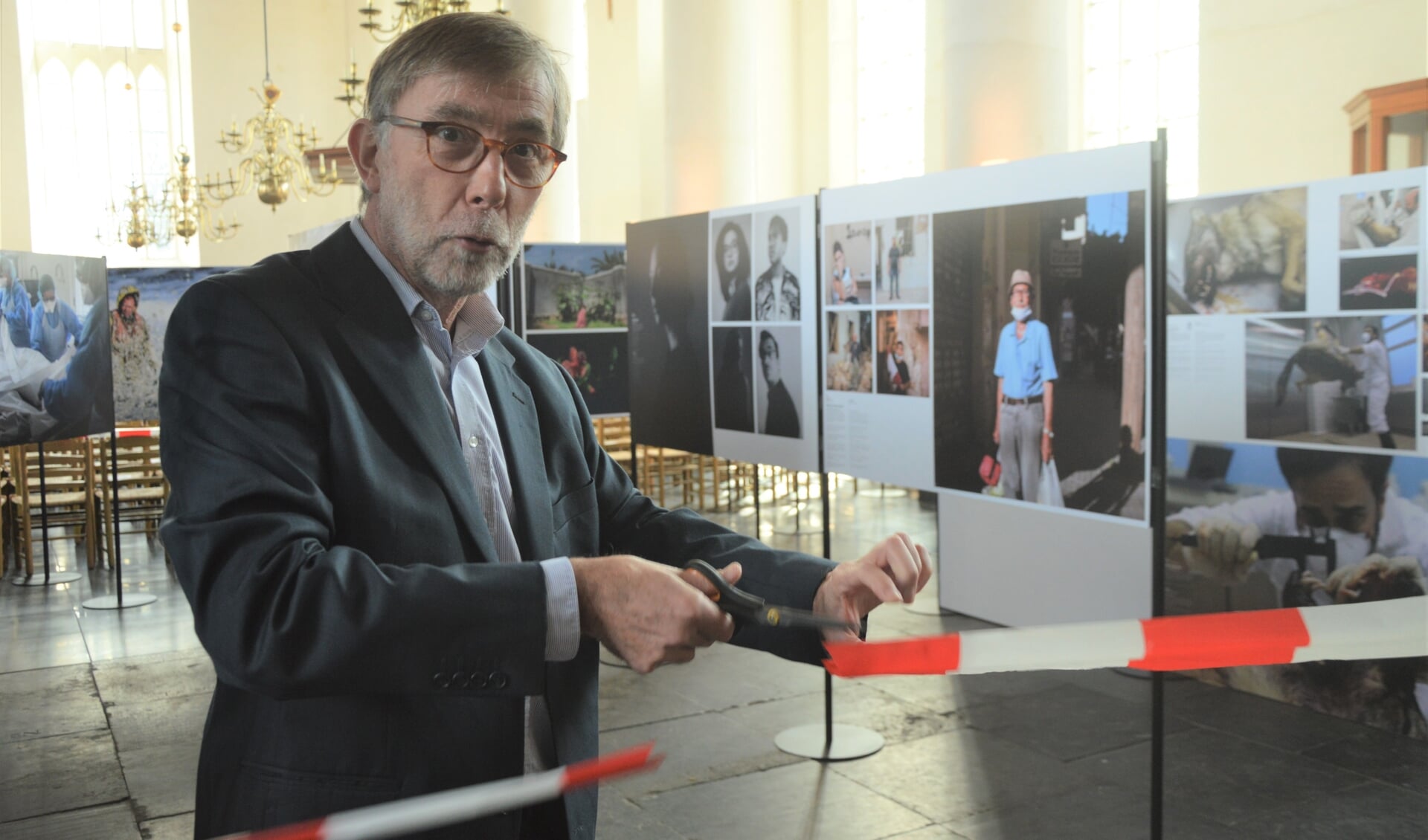 Met het doorknippen van het lint opent Werner Rauwerdink, secretaris van stichting Zilveren Camera de reizen de expositie in de Burghtkerk.