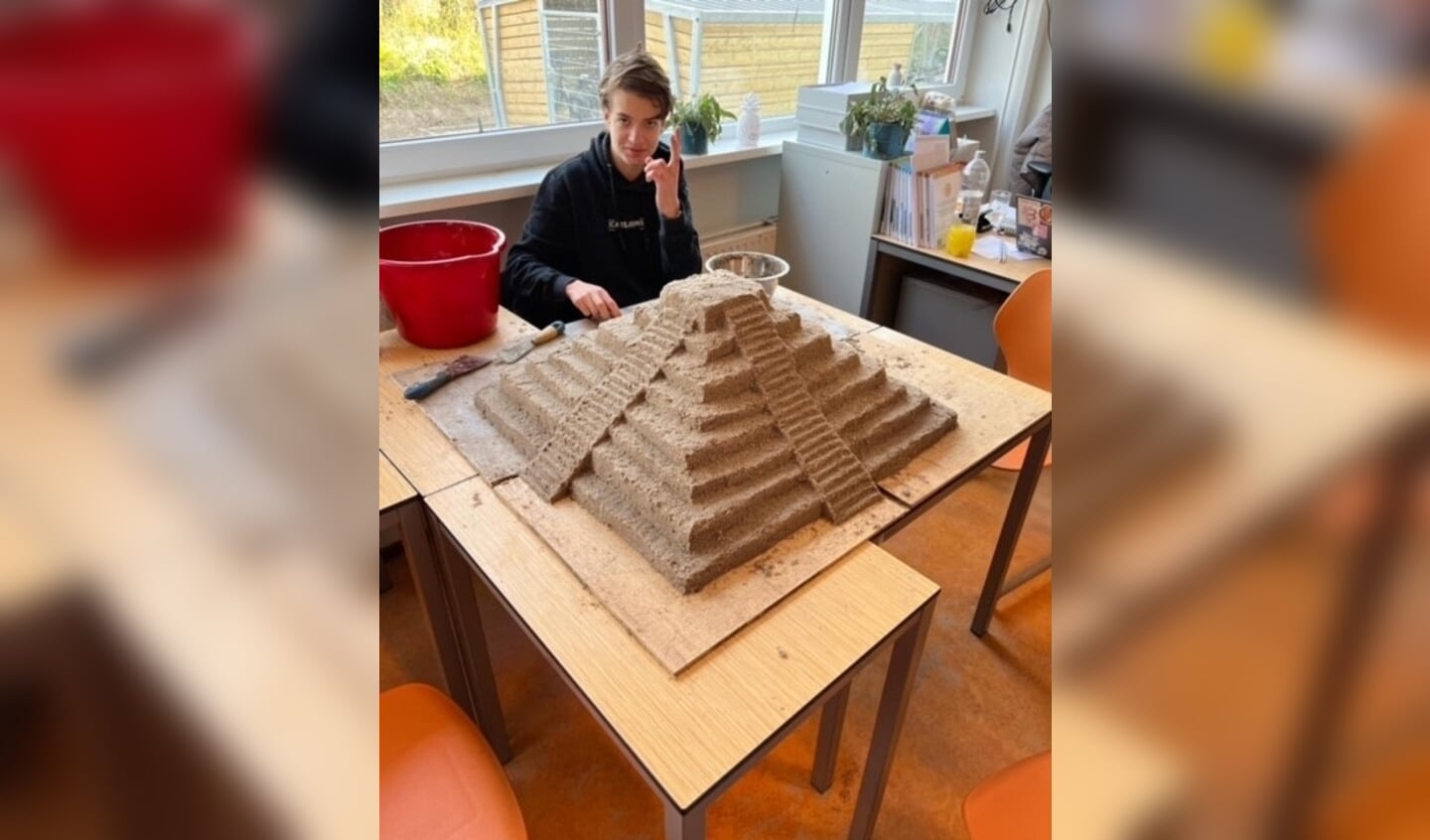 Een leerling bezig met een zandsculptuur.